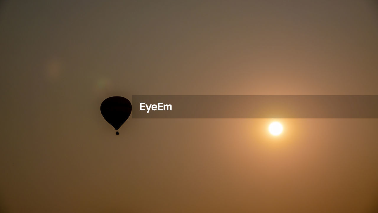LOW ANGLE VIEW OF HOT AIR BALLOON FLYING AGAINST SKY DURING SUNSET