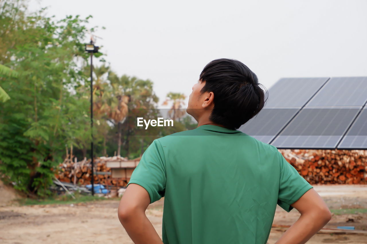 Rear view of boy standing against sky