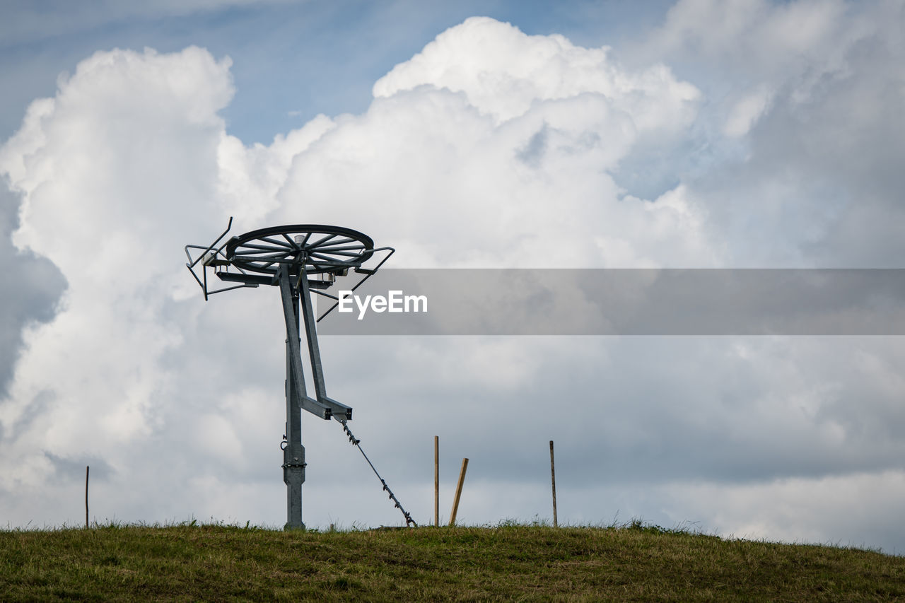 LOW ANGLE VIEW OF WIND TURBINES ON FIELD AGAINST SKY