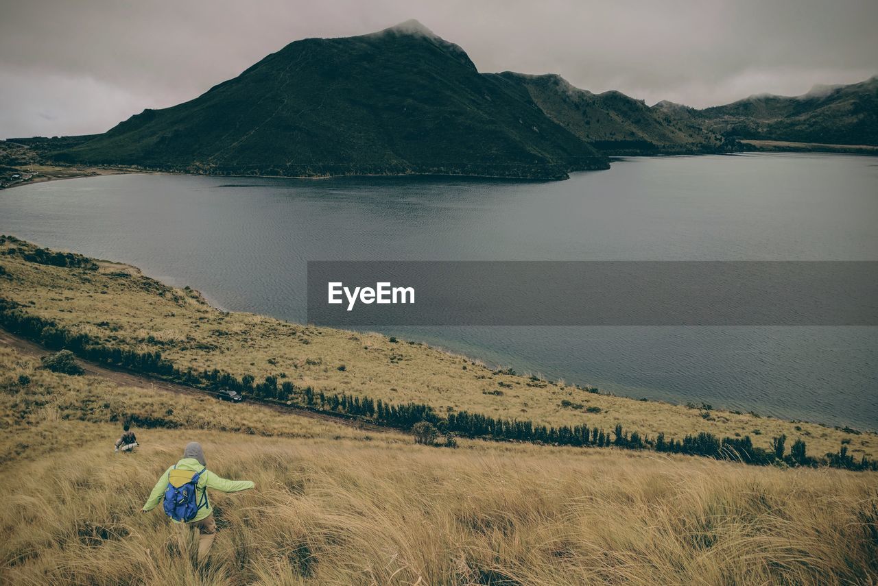 Person walking on mountain towards sea