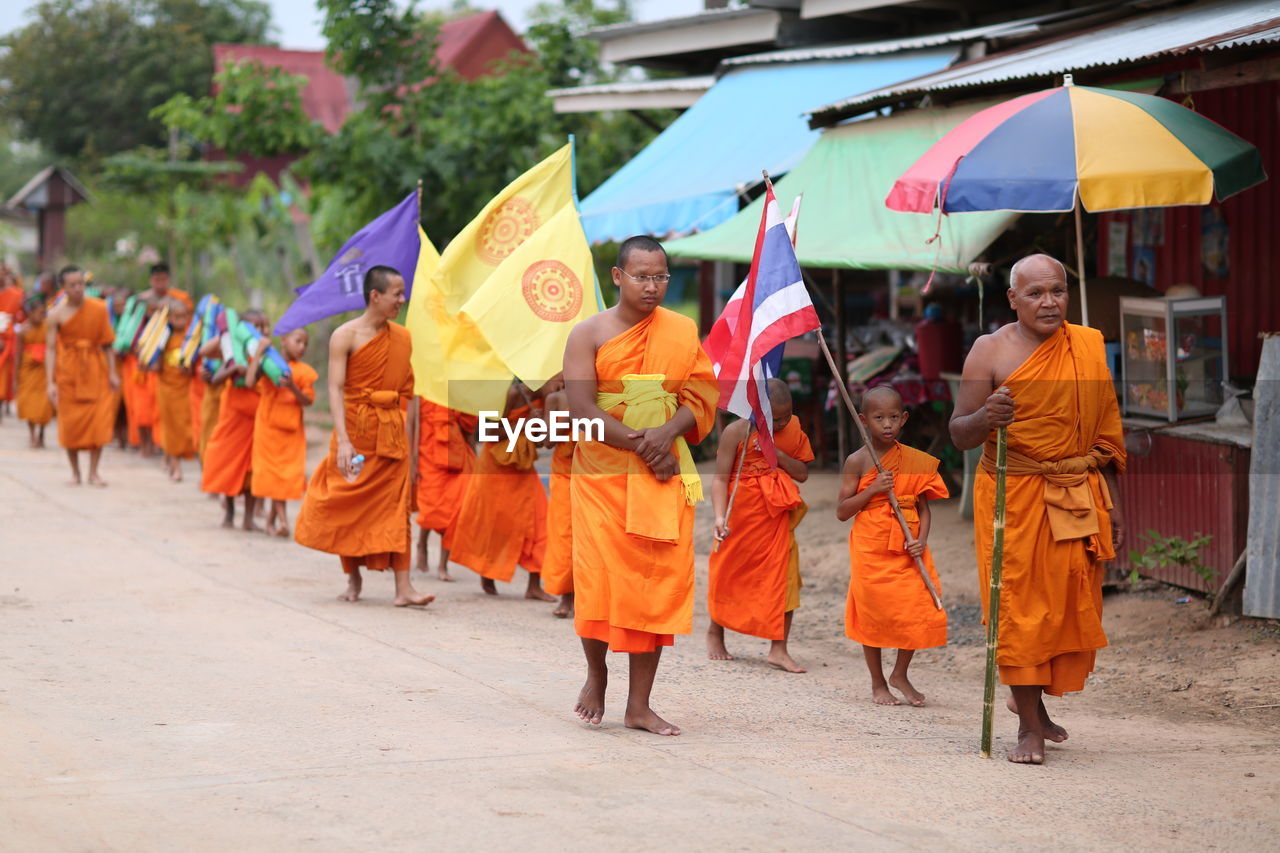 GROUP OF PEOPLE STANDING ON STREET AGAINST TREES