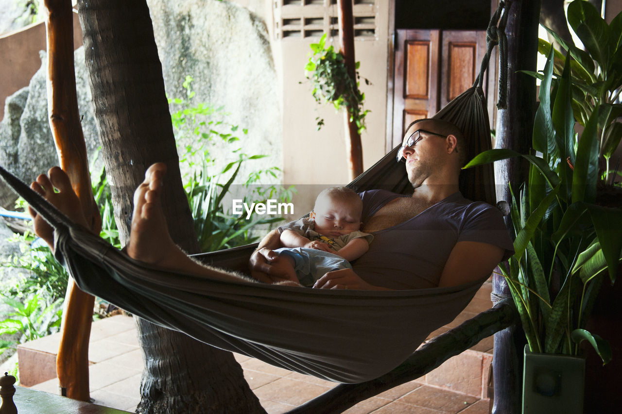 Father with baby seeping on hammock, thailand