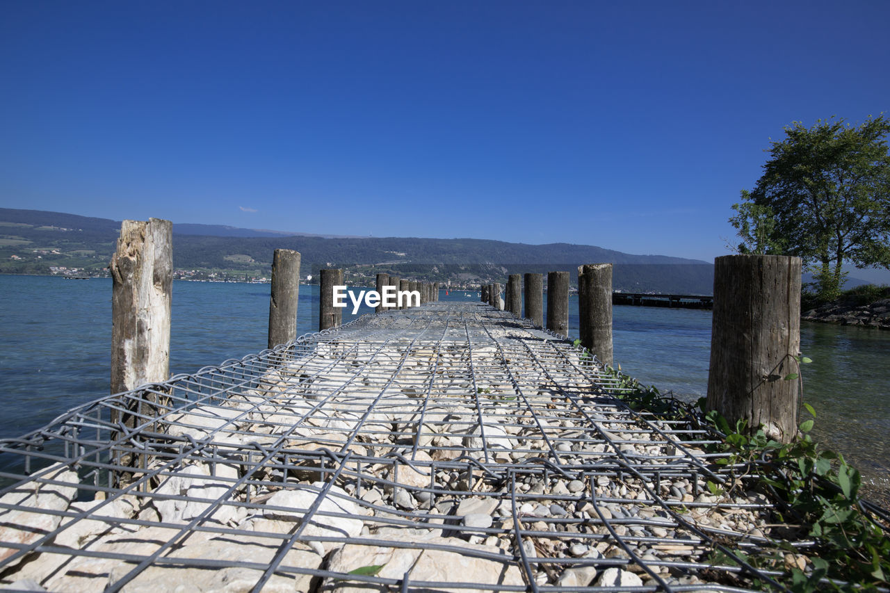 Pier over sea against clear blue sky