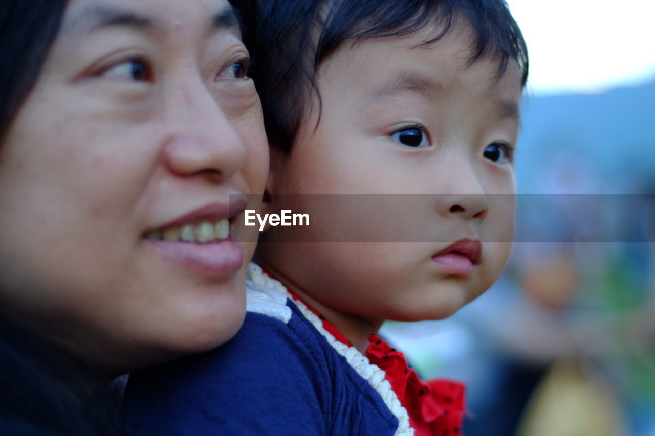 Close-up of woman with daughter looking away outdoors