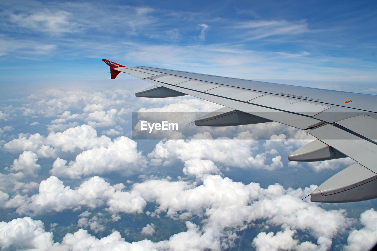 Cropped image of airplane flying over cloudscape against sky