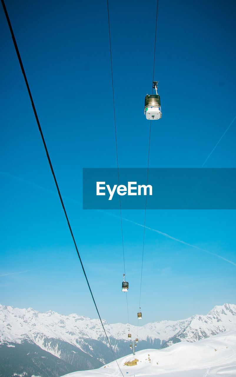 Low angle view of overhead cable car against blue sky