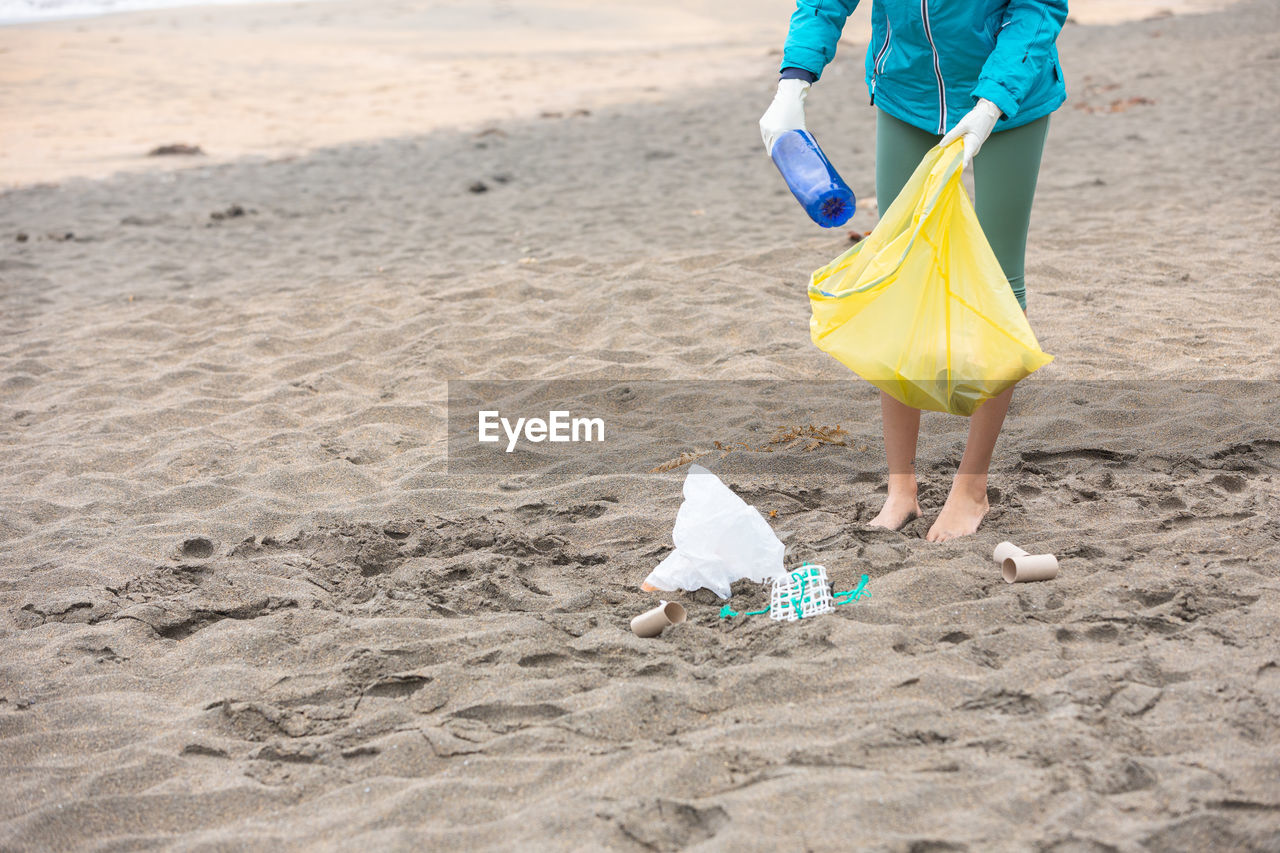 Crop unrecognizable female volunteer cleaning beach from garbage