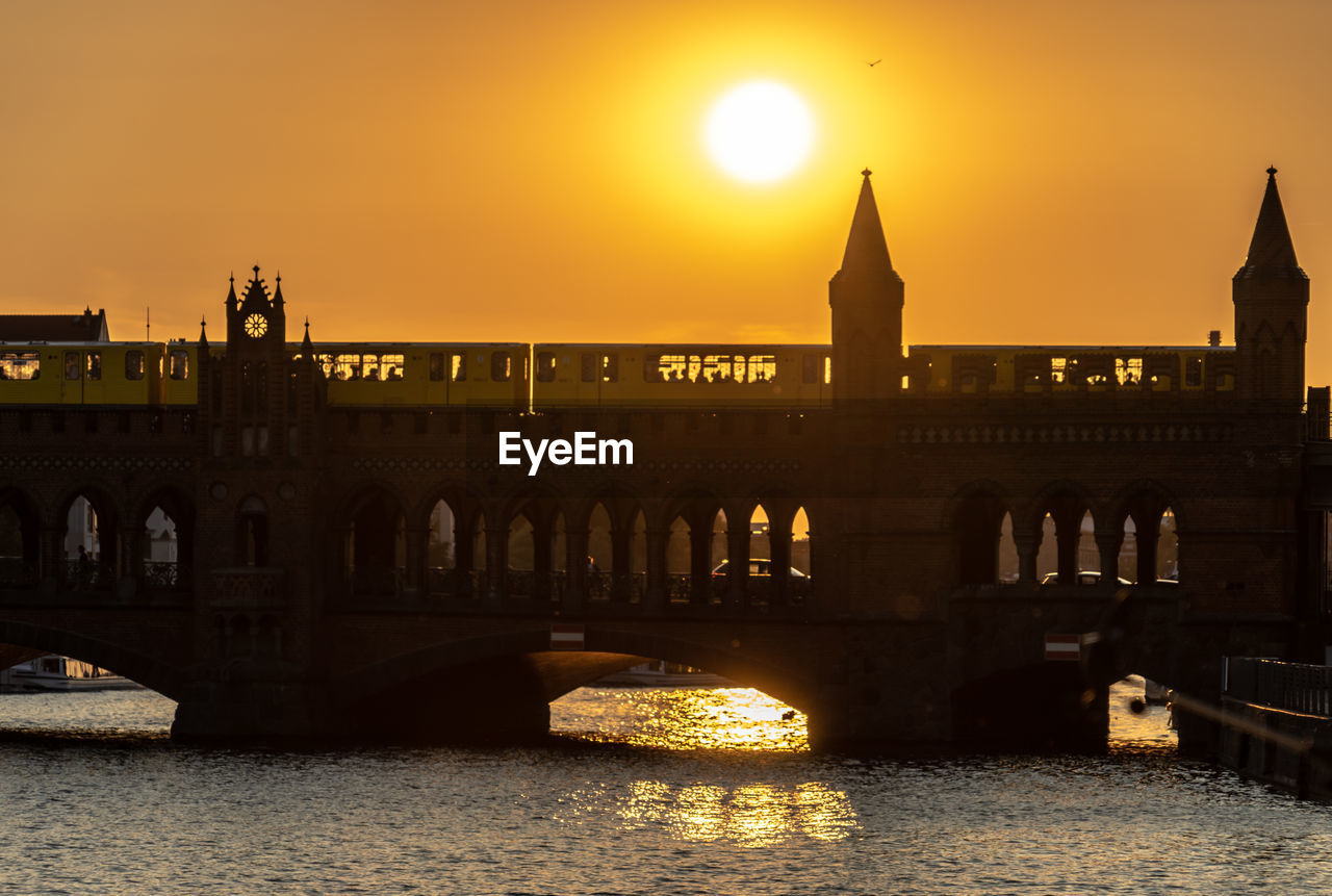 Arch bridge over river during sunset