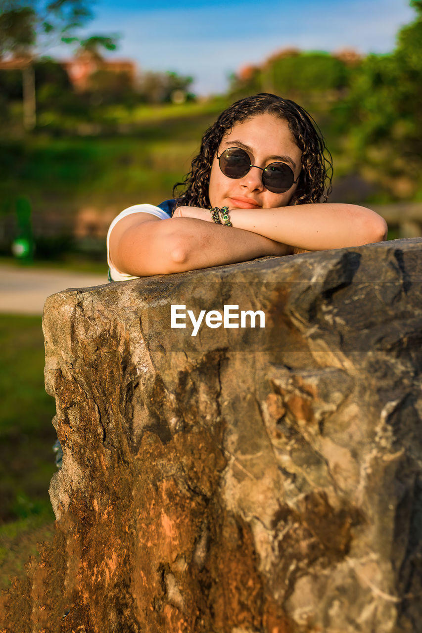 Portrait of young woman wearing sunglasses on rock