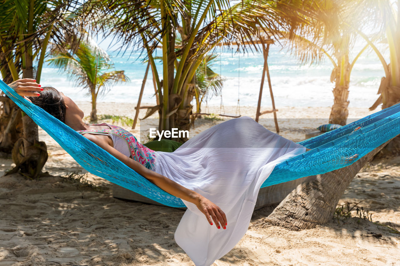 Young woman relaxing on hammock at beach