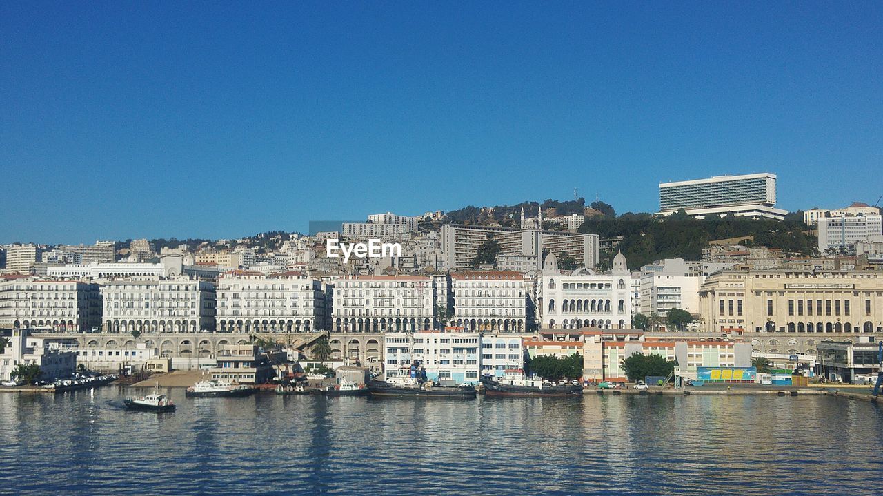 Buildings in city against clear blue sky