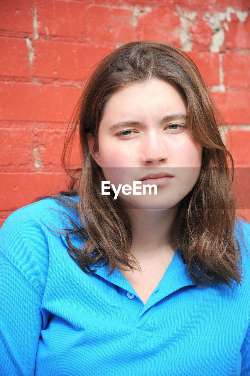 PORTRAIT OF A GIRL AGAINST WALL