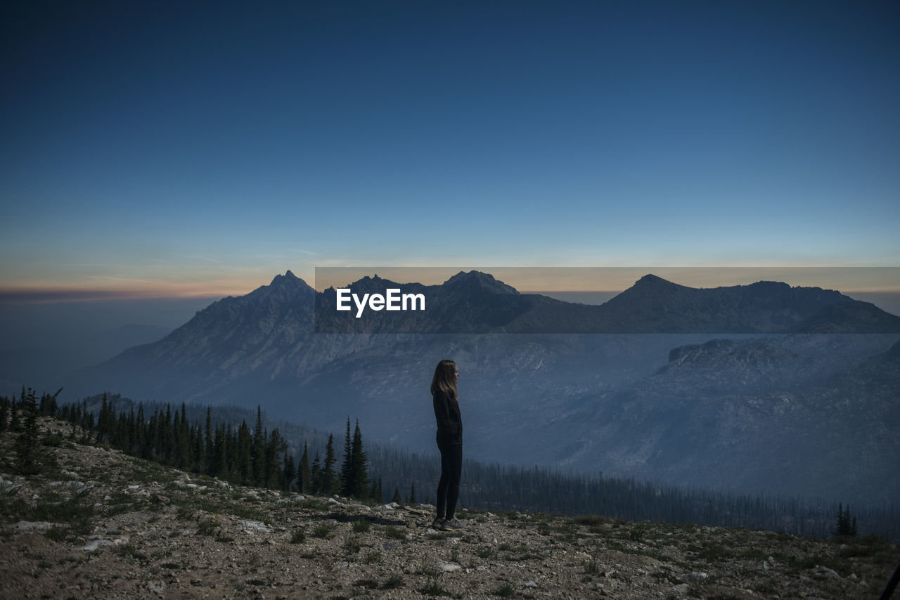 Side view of woman standing on cliff at sawtooth range