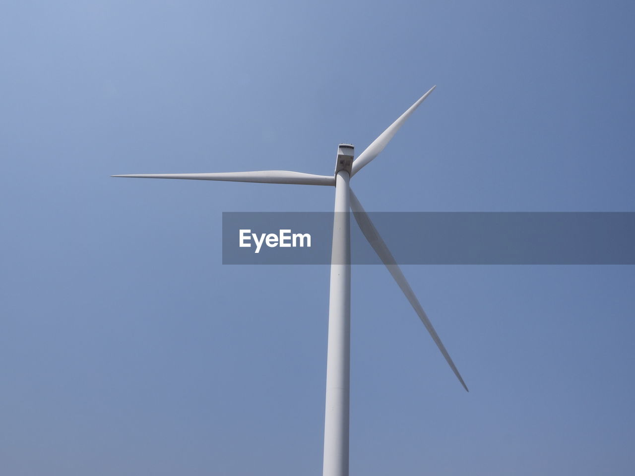 Low angle view of wind turbine against blue sky