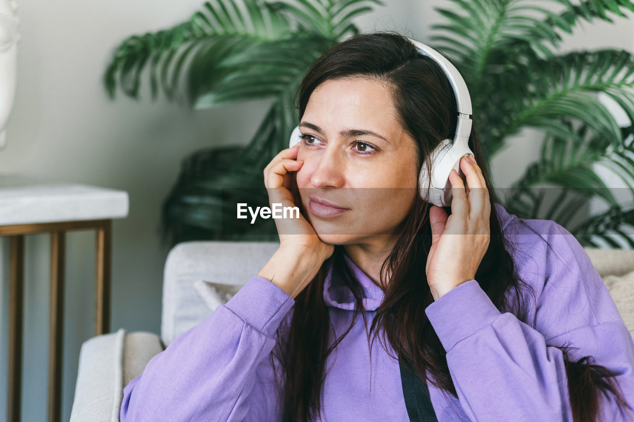 A woman in headphones listens to her favorite music at home on the couch.