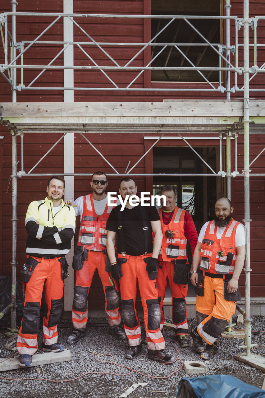 Full length of male construction workers standing together at site