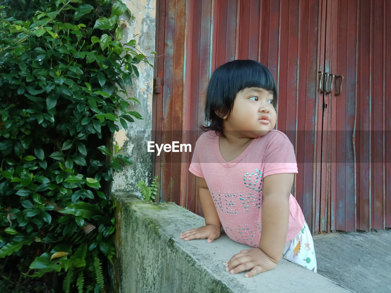 CUTE GIRL LOOKING AWAY WHILE SITTING IN PARK