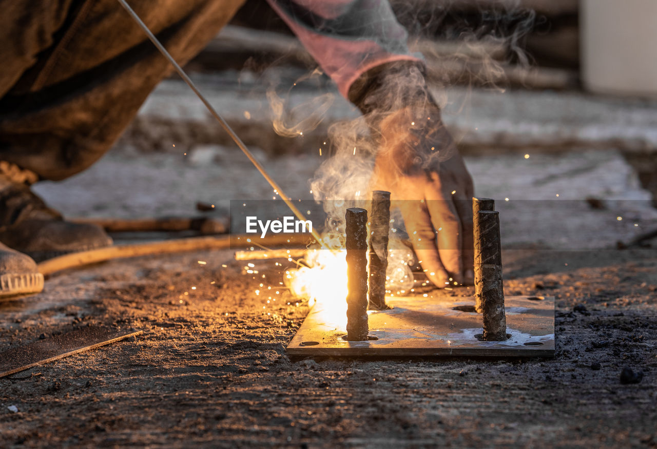 Low section of worker welding metal in workshop