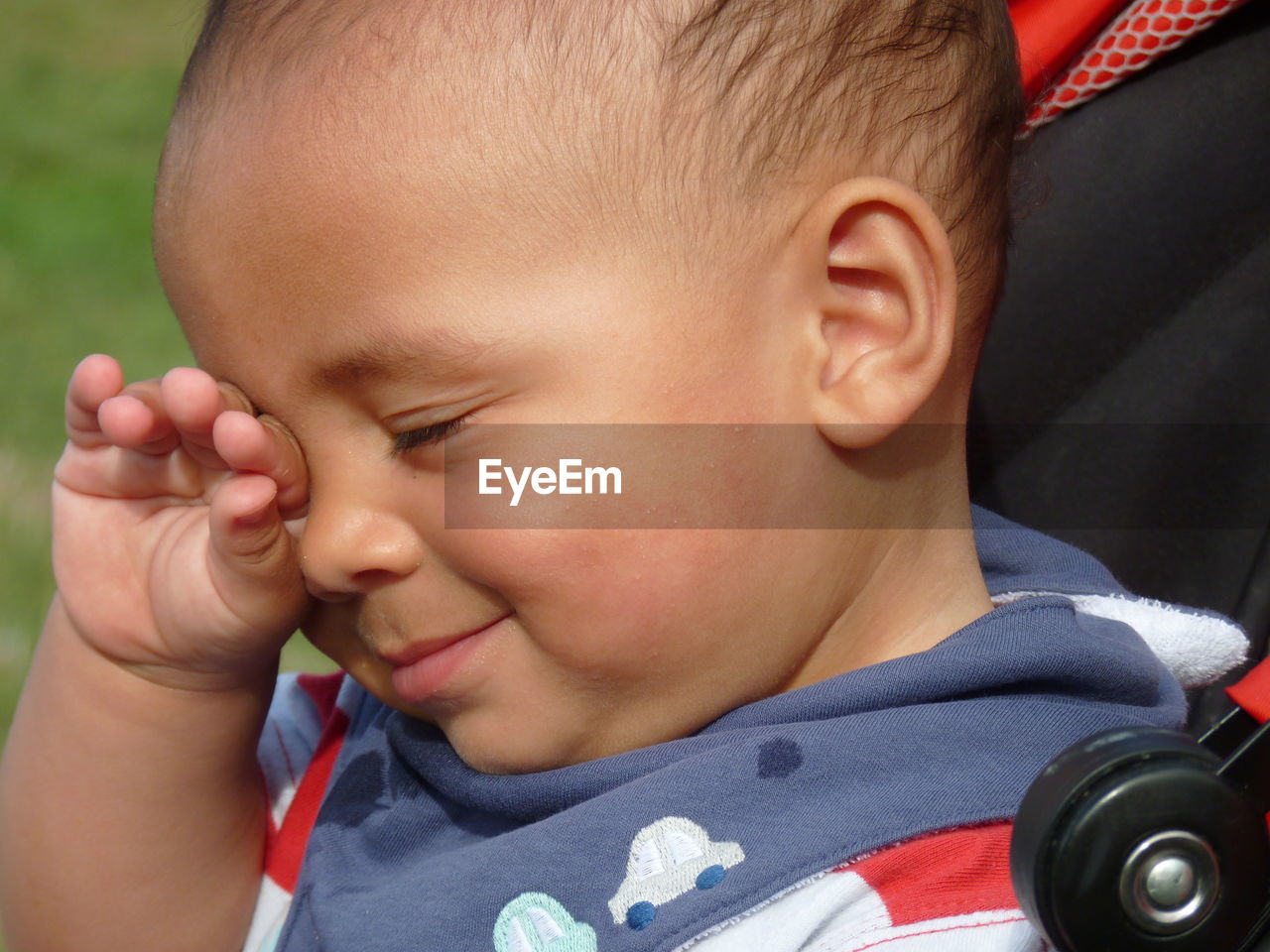 Close-up of cute smiling boy rubbing eyes