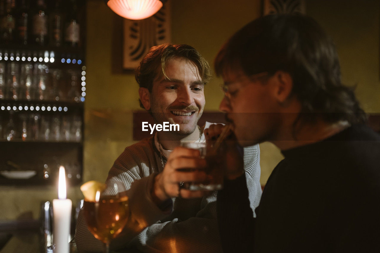 Gay man tasting boyfriend's drink at bar
