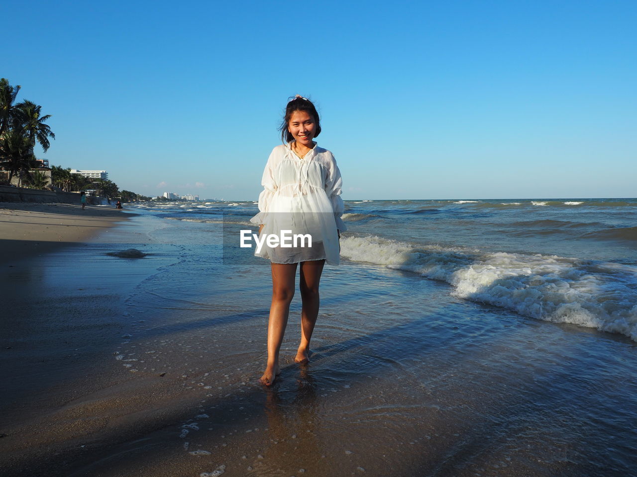 Full length portrait of woman standing on beach against clear sky
