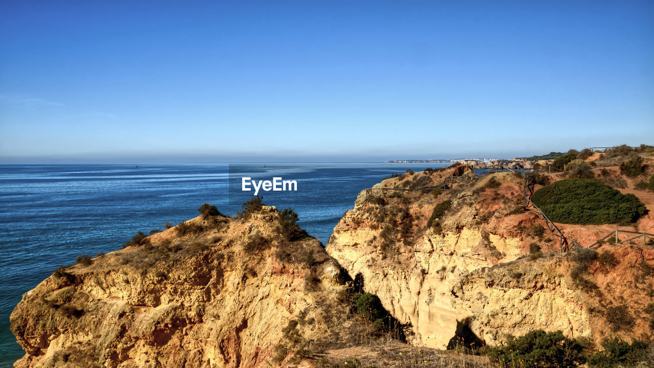 Scenic view of rocky beach against clear blue sky