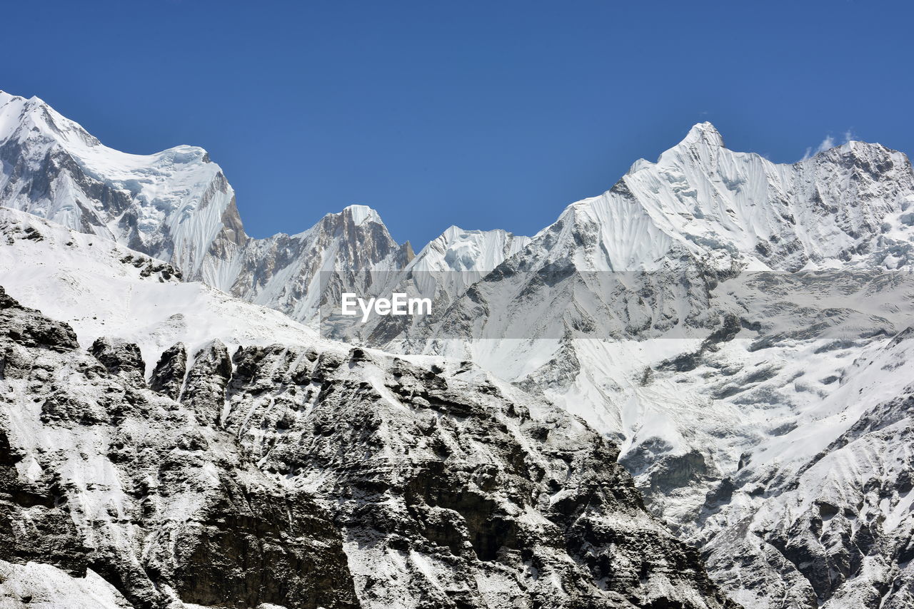 Scenic view of snowcapped mountains against clear blue sky