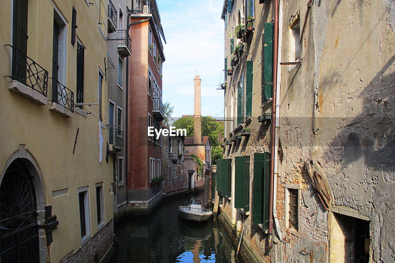 Canal amidst buildings in city against sky