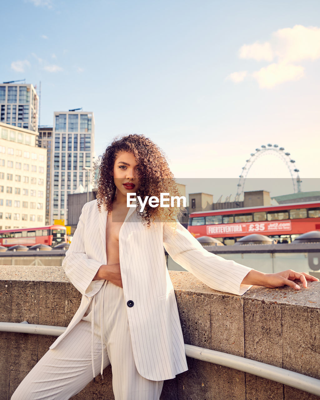 YOUNG WOMAN STANDING AGAINST BUILDINGS IN CITY