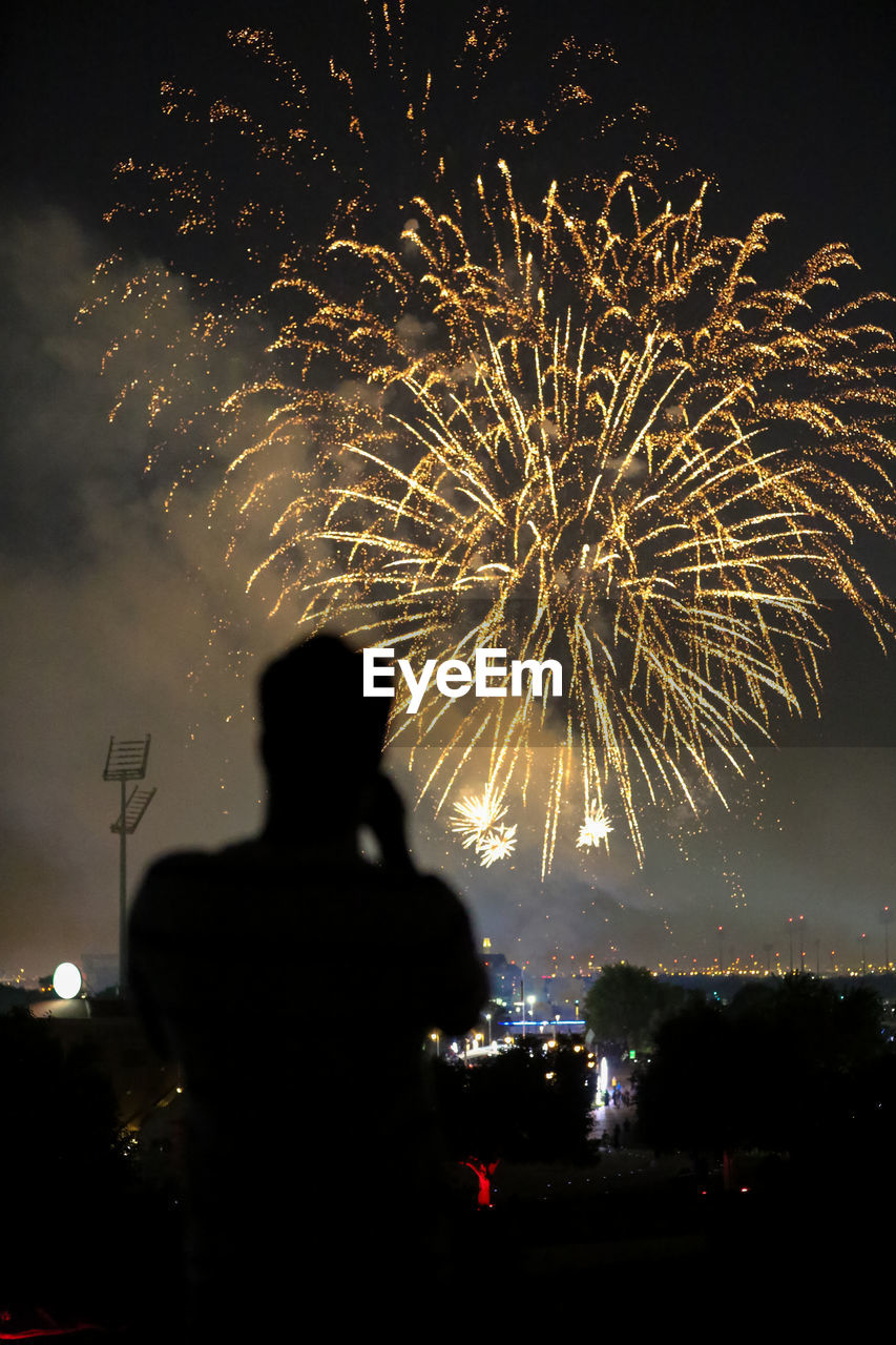 REAR VIEW OF SILHOUETTE FIREWORKS AGAINST SKY