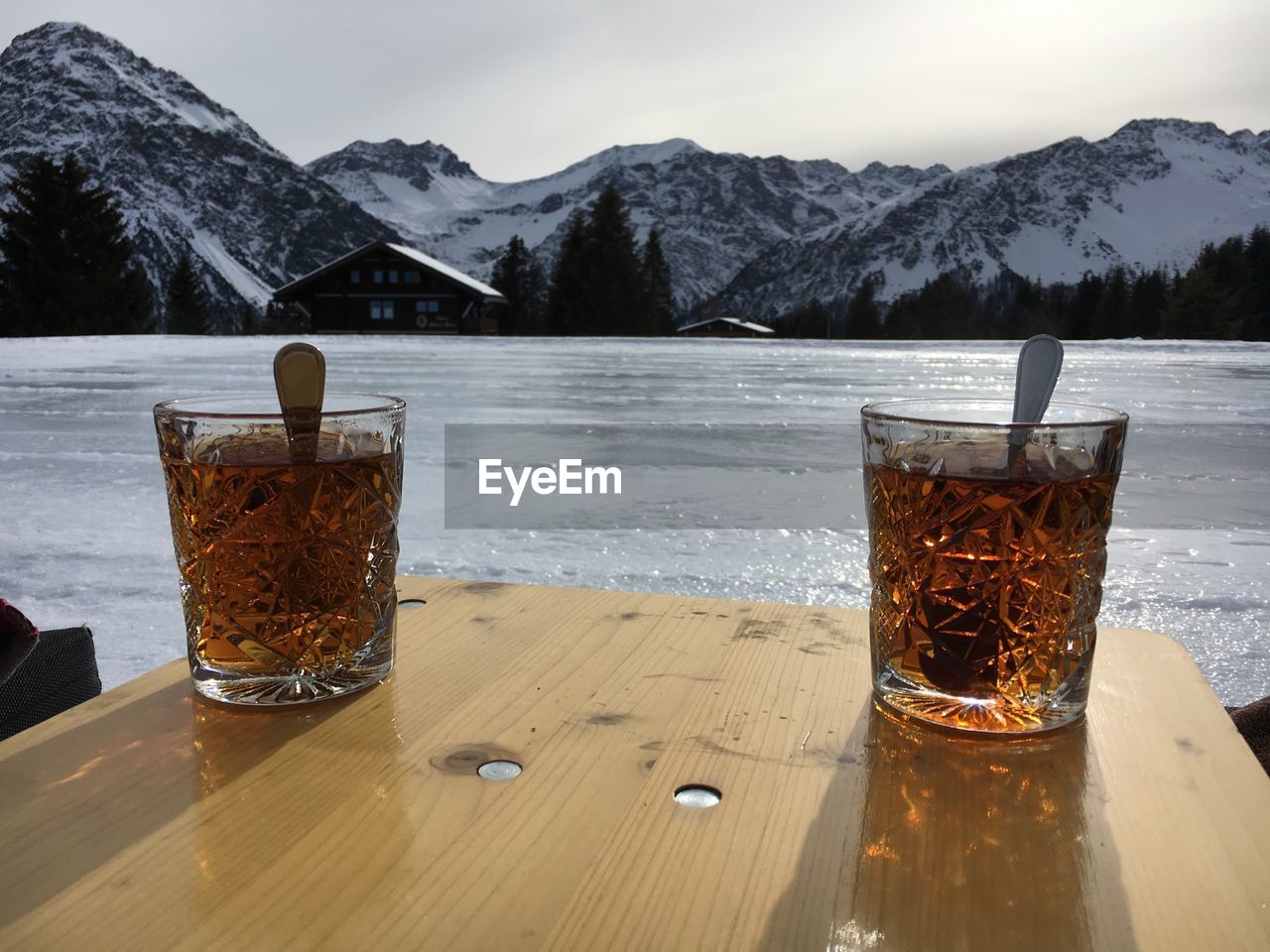 CLOSE-UP OF BEER ON TABLE AGAINST MOUNTAINS