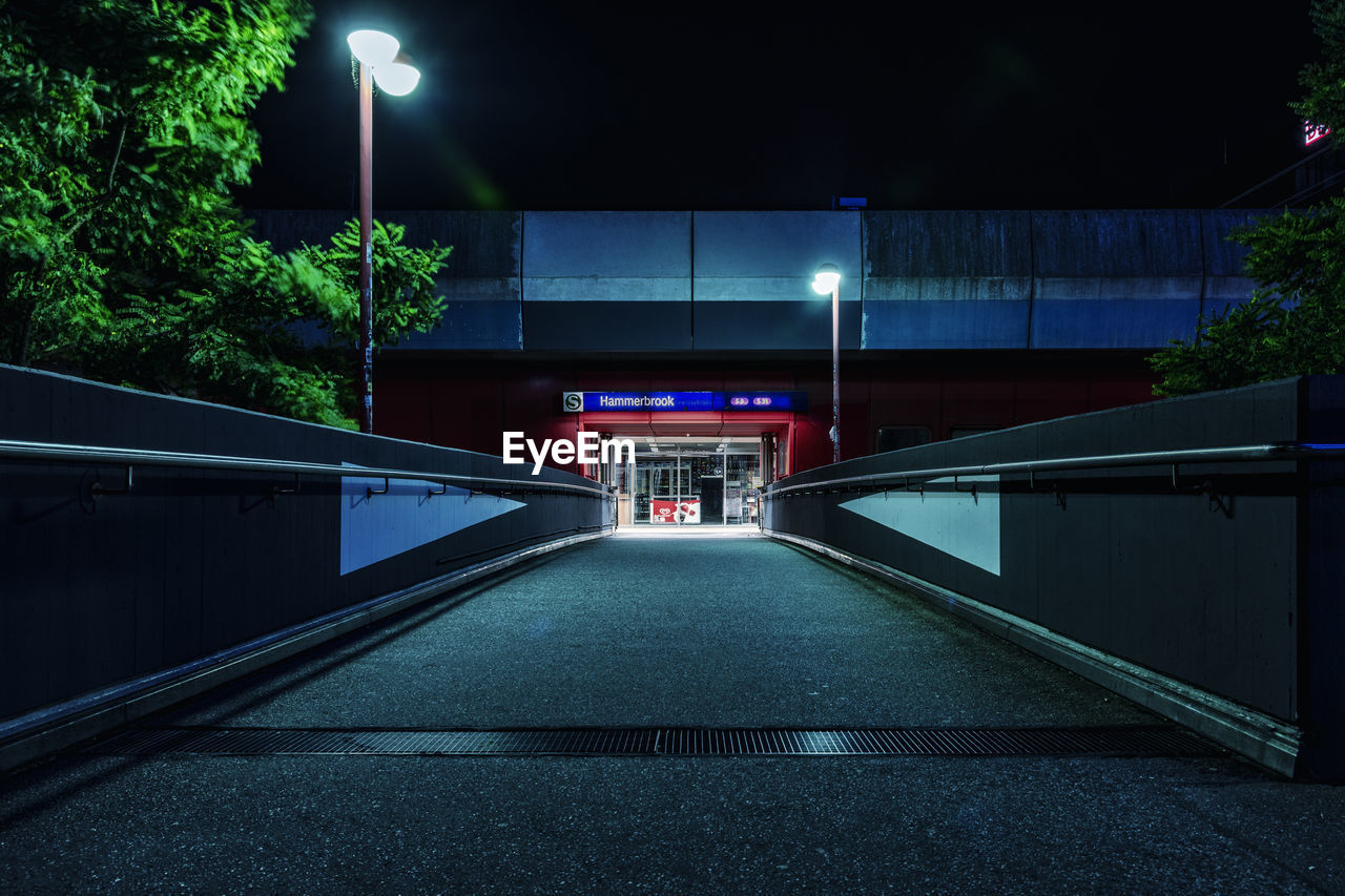 Empty road leading towards building at night