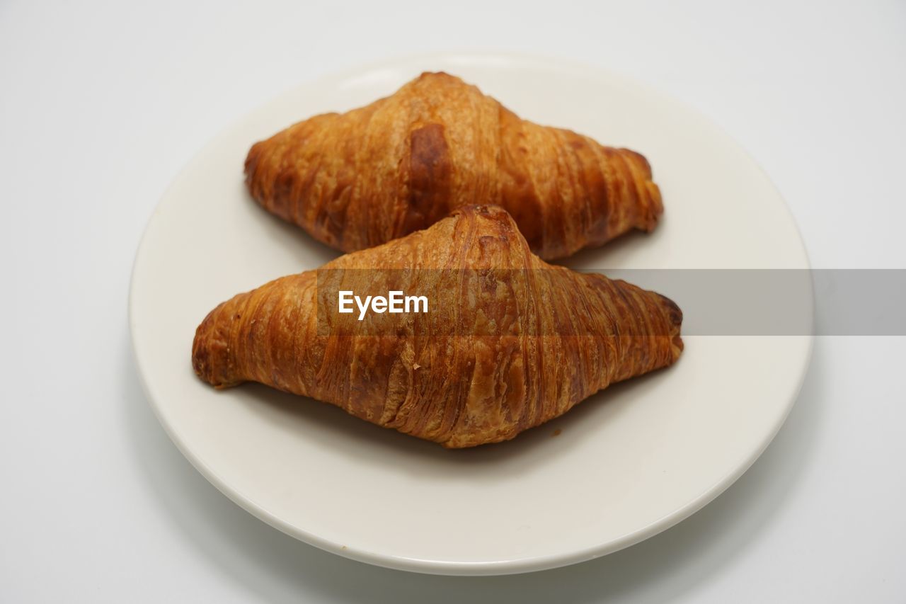 Close-up of croissants in plate over white background