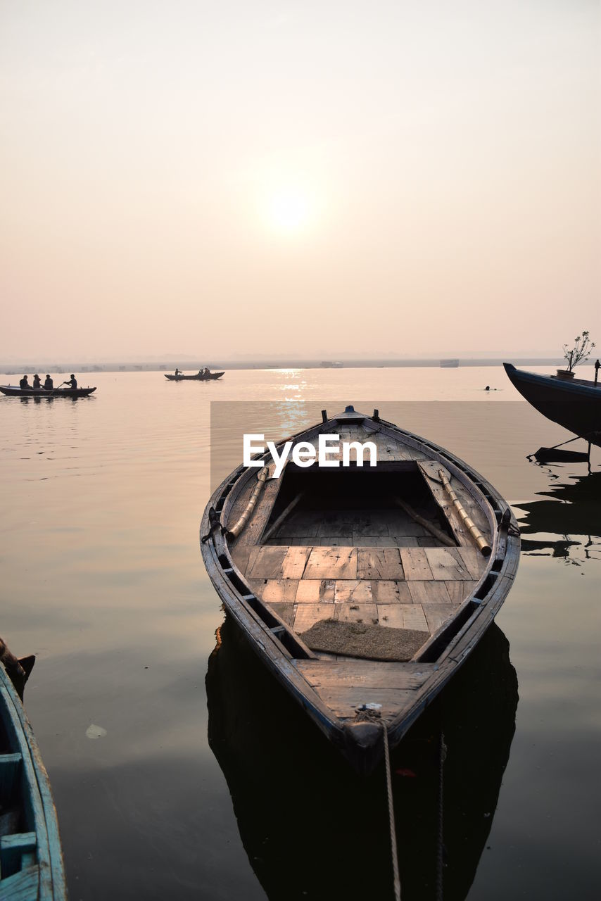 BOATS MOORED IN SEA AGAINST SKY DURING SUNSET