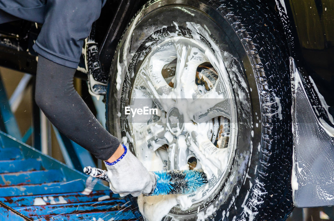 Cropped hand of person washing car tire