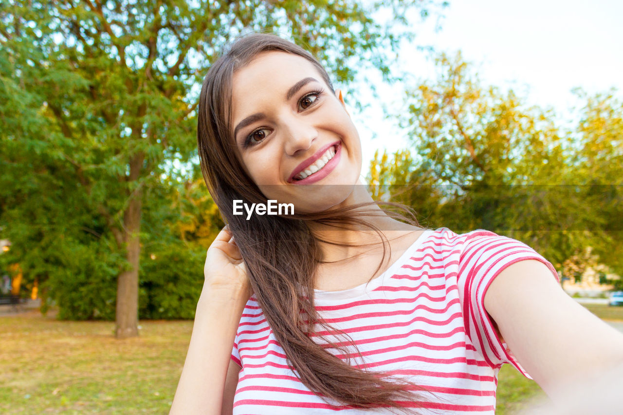 Portrait of smiling beautiful woman standing at park