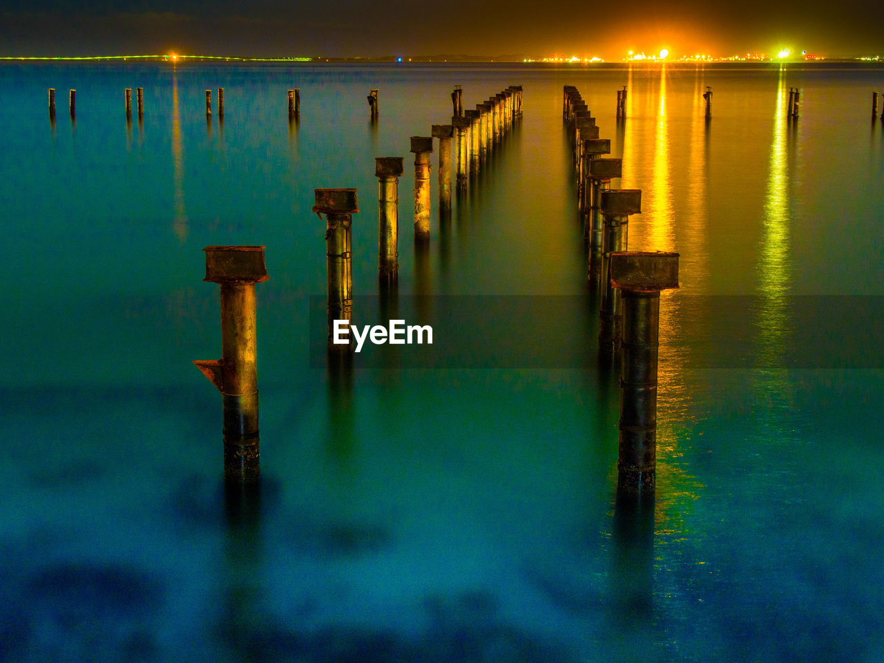 Wooden posts in ocean at night