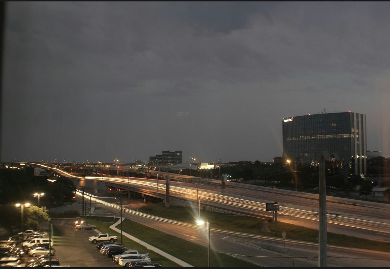 ROAD PASSING THROUGH ILLUMINATED CITY AT NIGHT