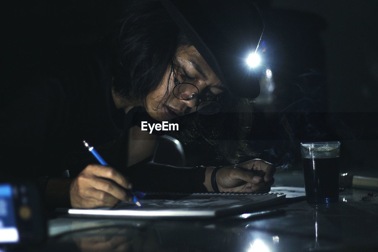 Man smoking cigarette while writing in book