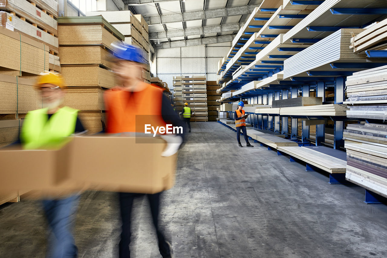 Workers moving and carrying boxes in factory warehouse