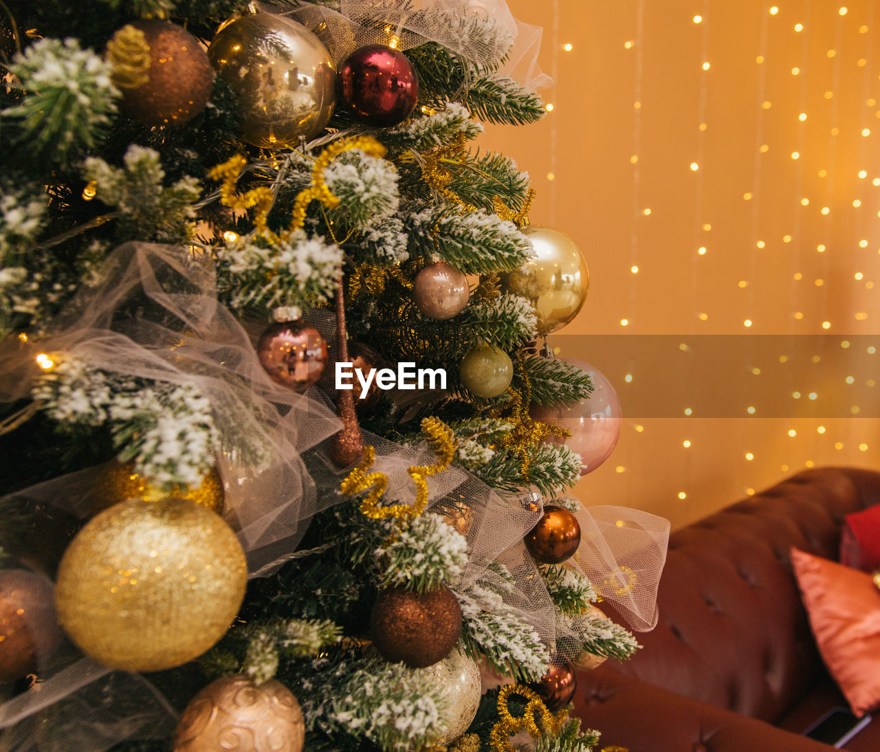 A christmas tree festively decorated with toys stands against  of the interior of the room.