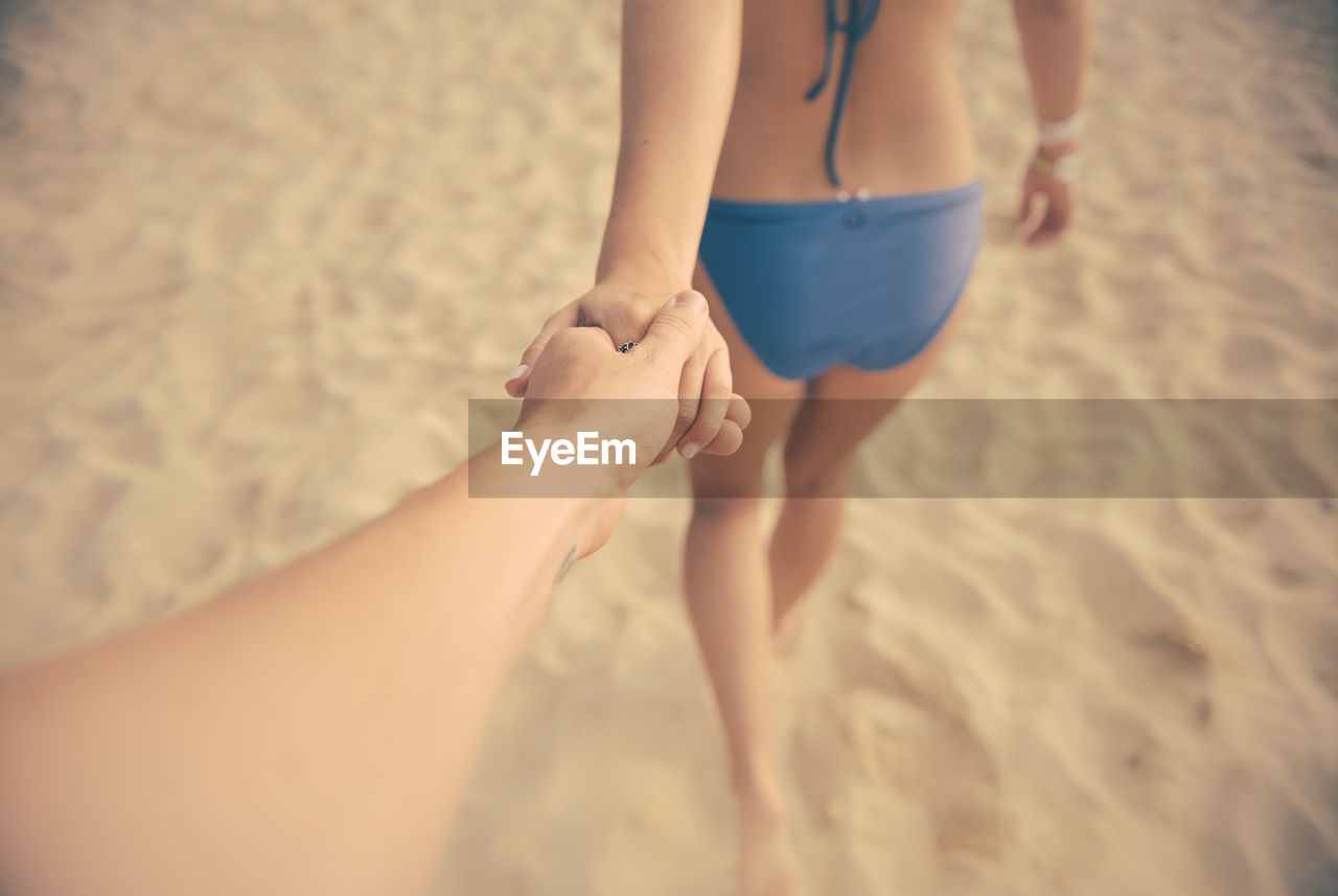 Cropped image of couple holding hands at beach