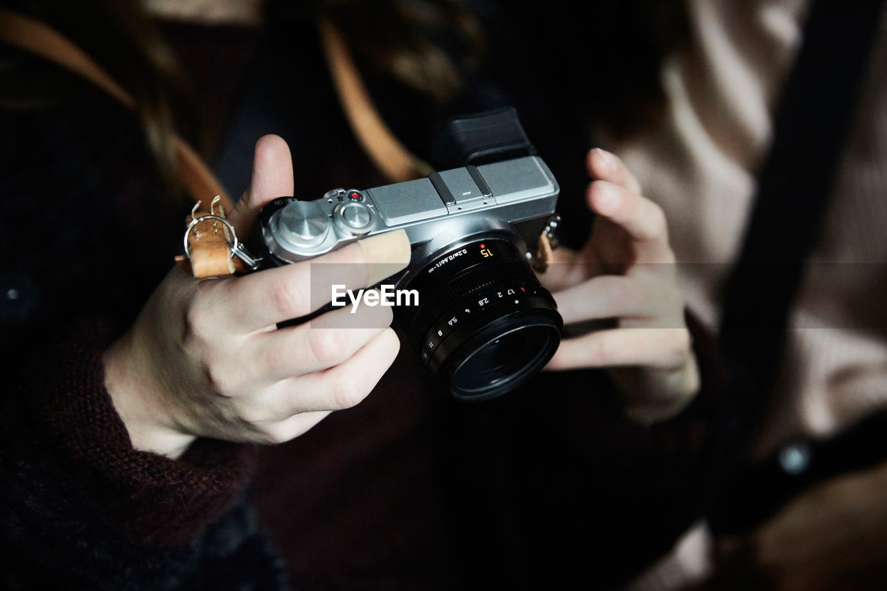 Midsection of woman holding camera while sitting with friend in taxi