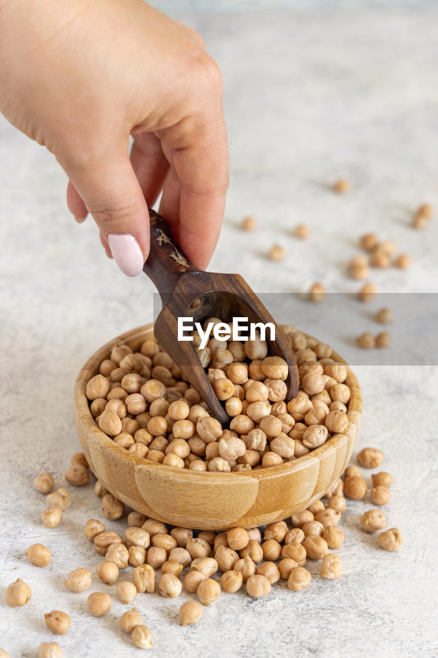 Hand with a scoop of raw dry chickpea close up