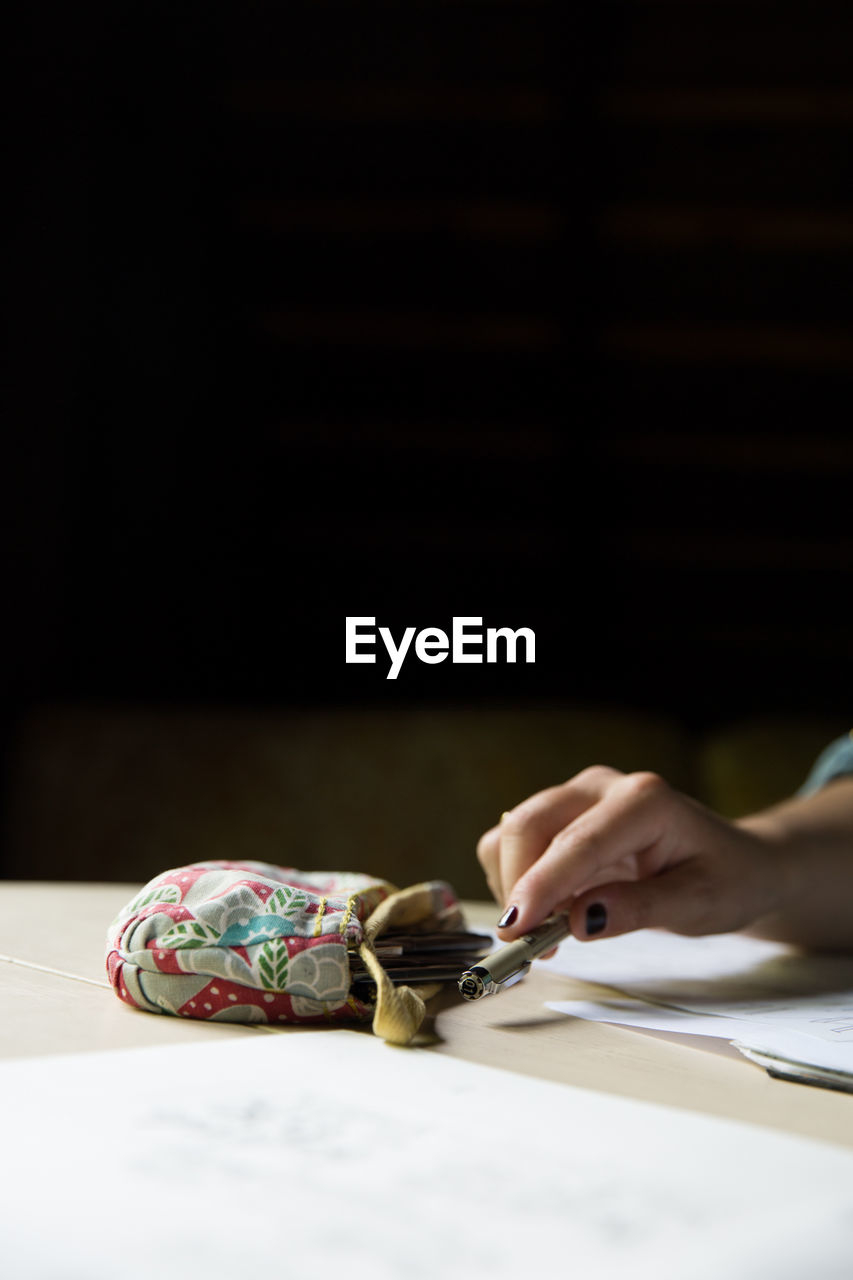 Cropped image of woman holding pen on table