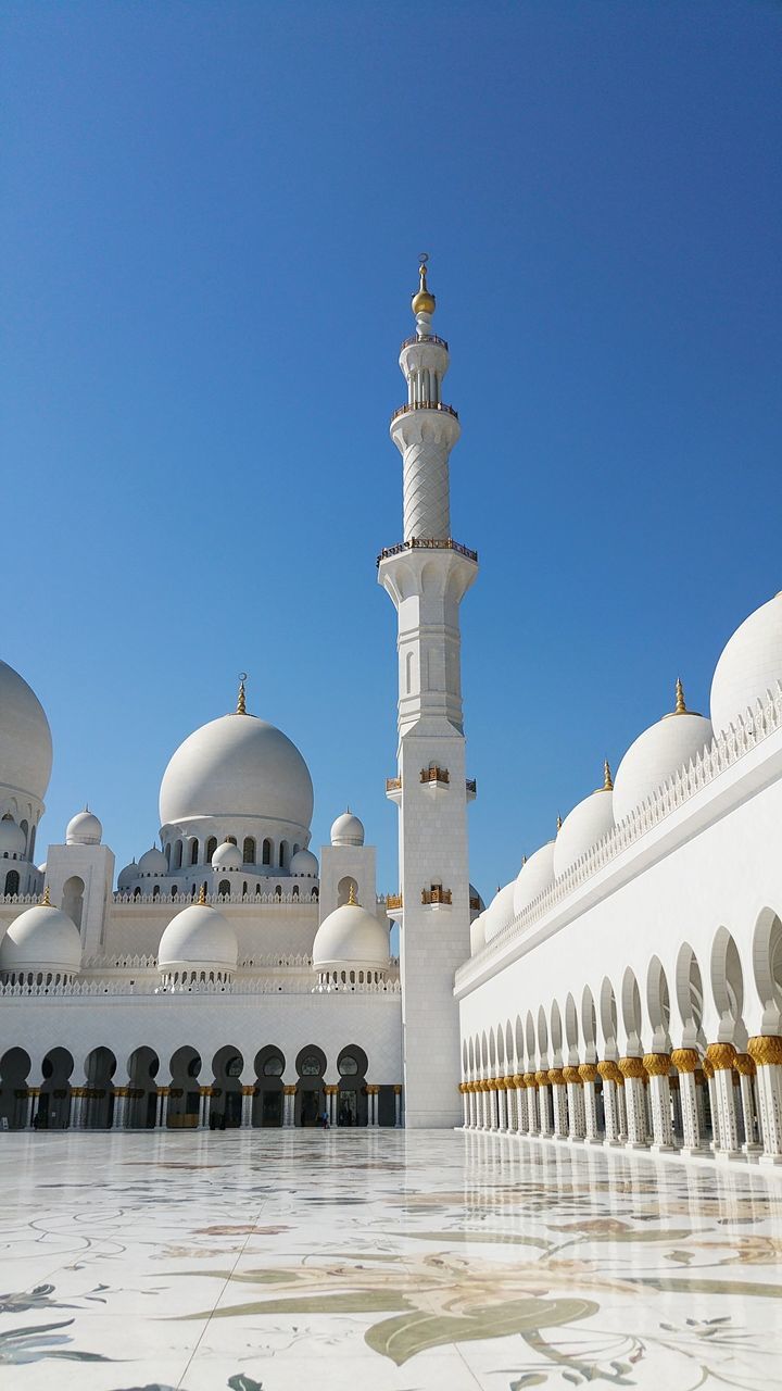 Mosque building against blue sky during sunny day