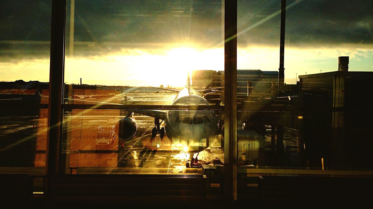 Airplane on airport runway against sunset