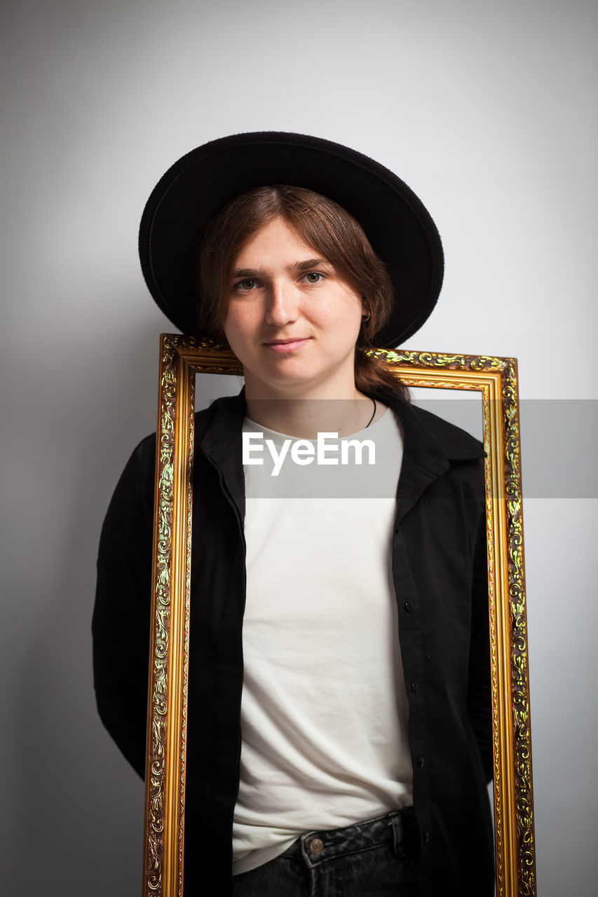 Artistic portrait, frame within a frame, young woman. beyond the frame, emotional studio shot
