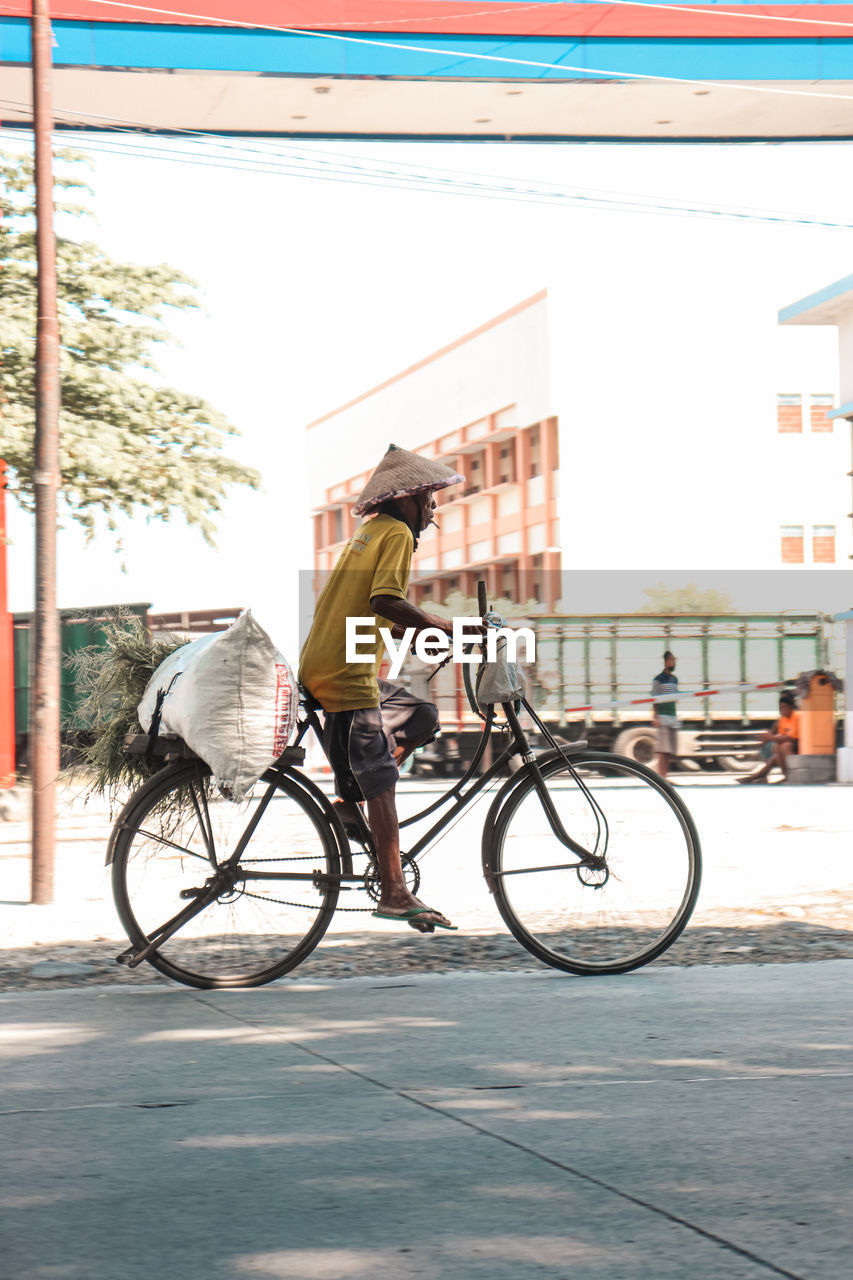 Side view of man riding bicycle on street