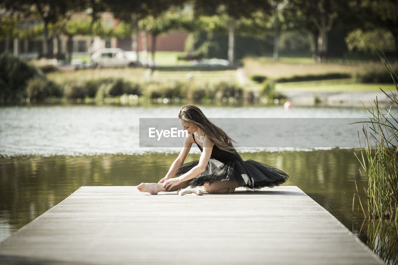 Woman in ballerina costume on pier over lake